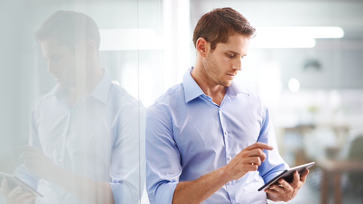 man standing by wall using tablet