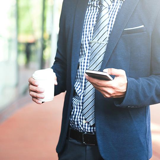 Pourquoi l'impression reste essentielle businessman holding a coffee and mobile phone